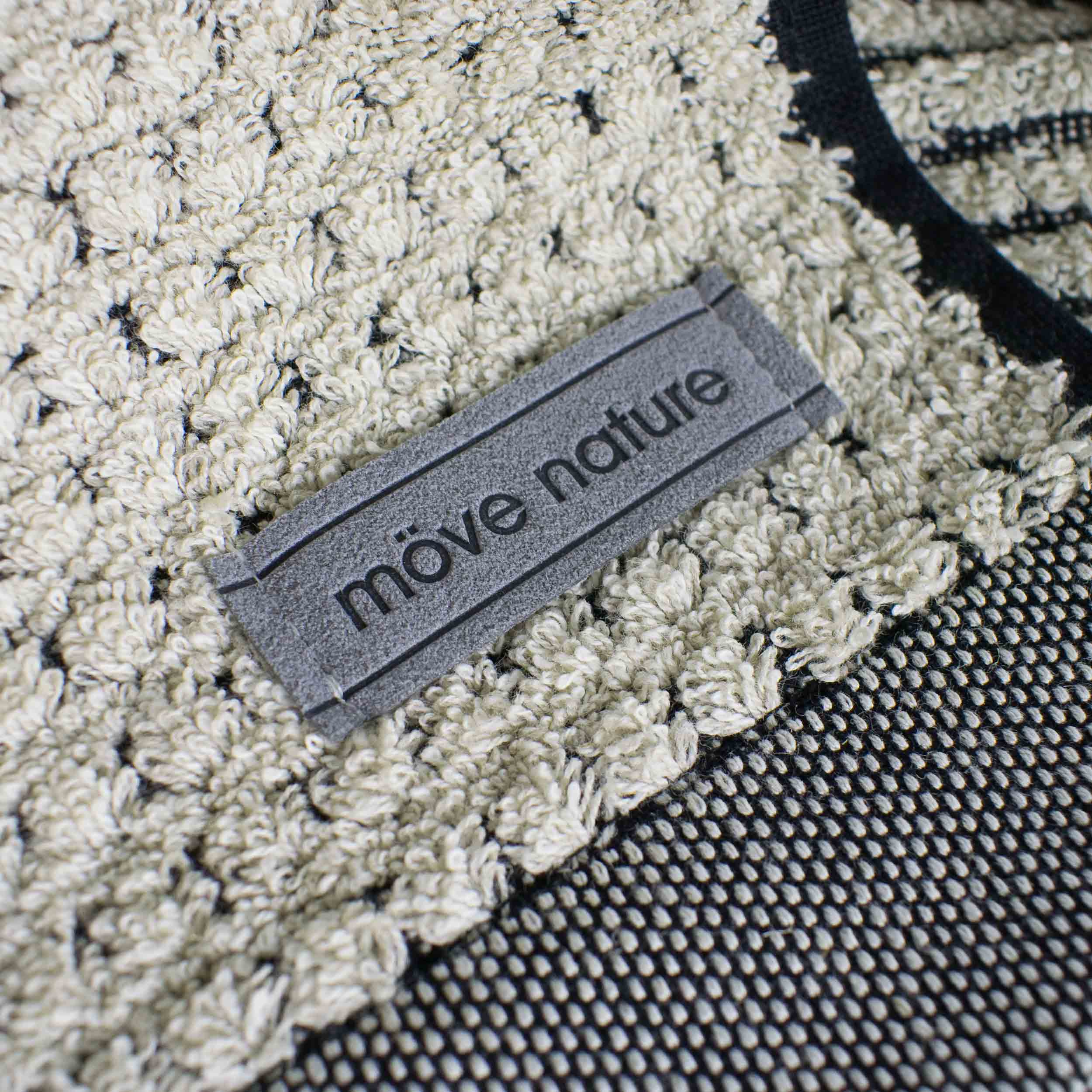 Towel with a sewn-on “möve nature” label; close-up shows a woven, looped terry cloth texture in light beige, alongside dark, finely woven fabric.