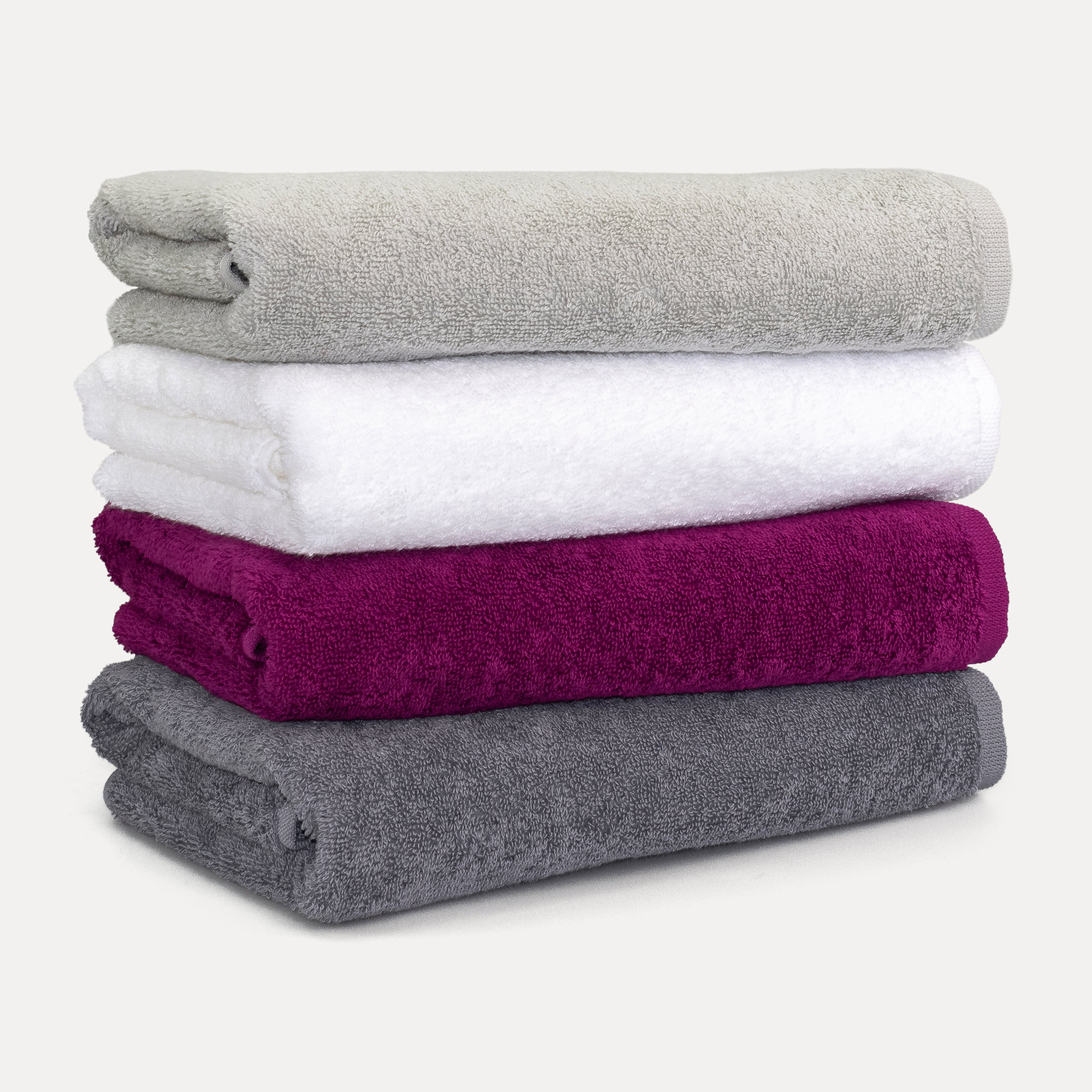 Stacked towels (white, green) lie on a wooden bench; a green towel hangs off the side. Context: bright bathroom with a recessed niche (candle, decor) and stepped floor.