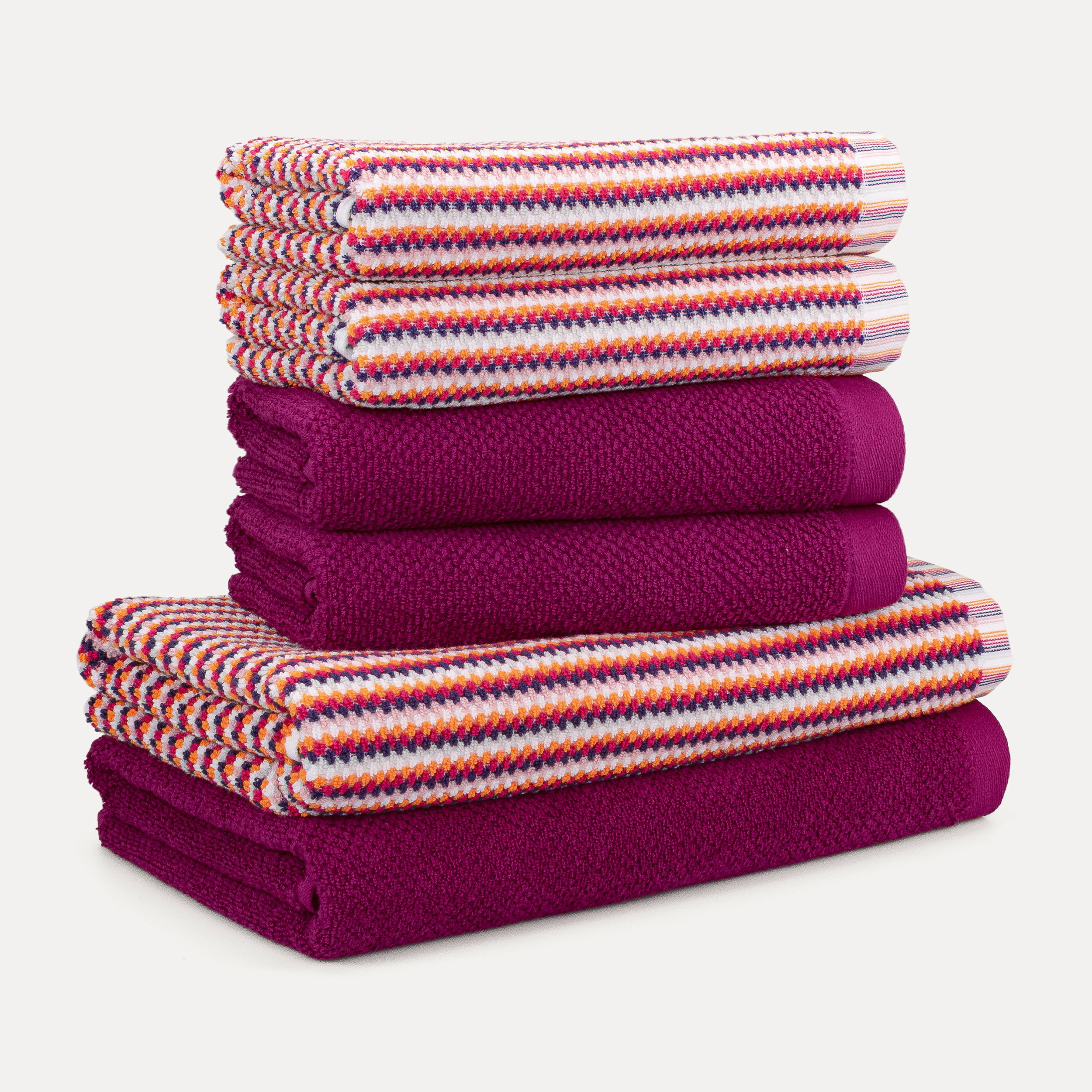 Towels — two multicolored striped and three solid magenta towels are neatly folded into a stack; simple studio product shot against a white background.
