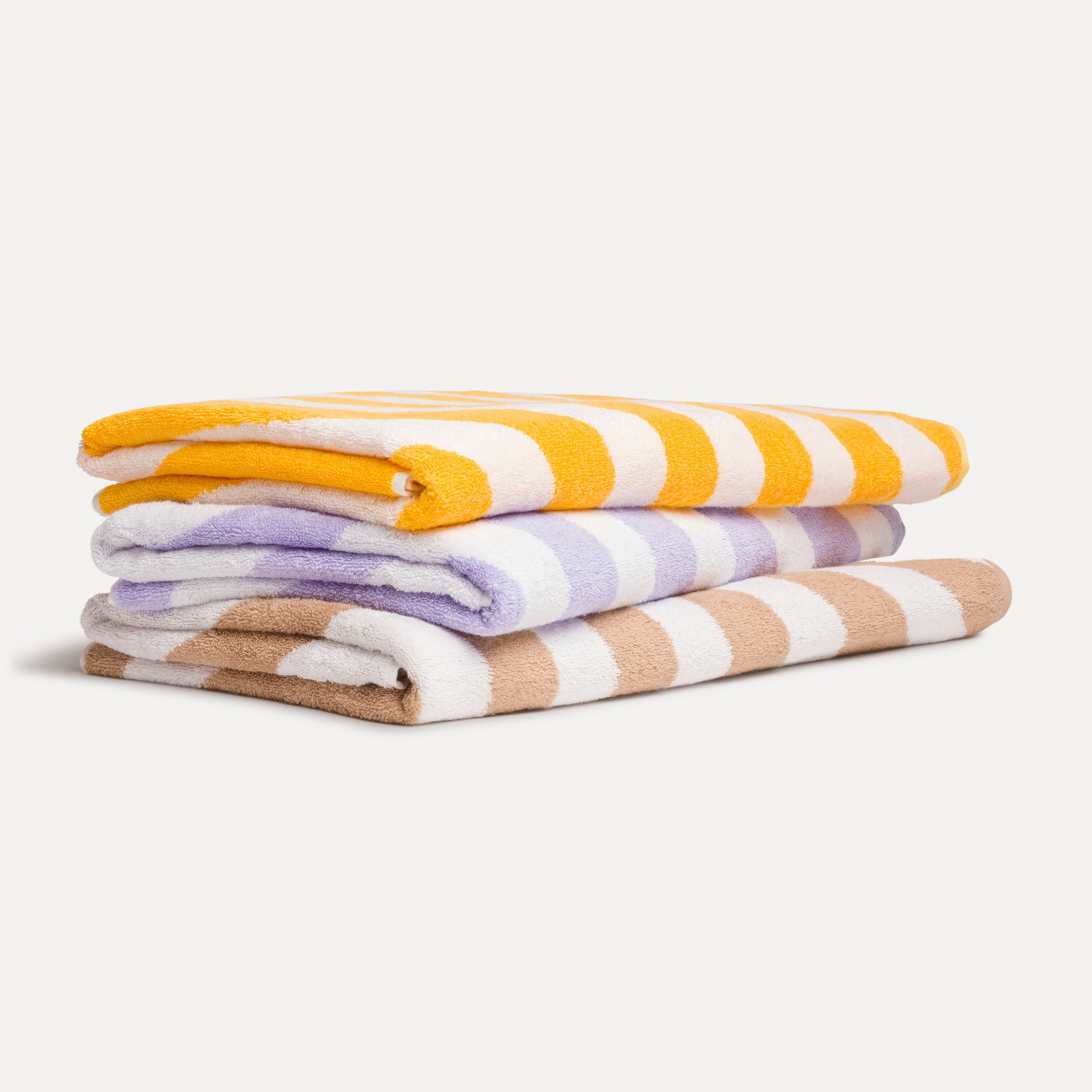 Three folded bath towels with white stripes (yellow, lilac, beige) are stacked and lying on a light, neutral background.