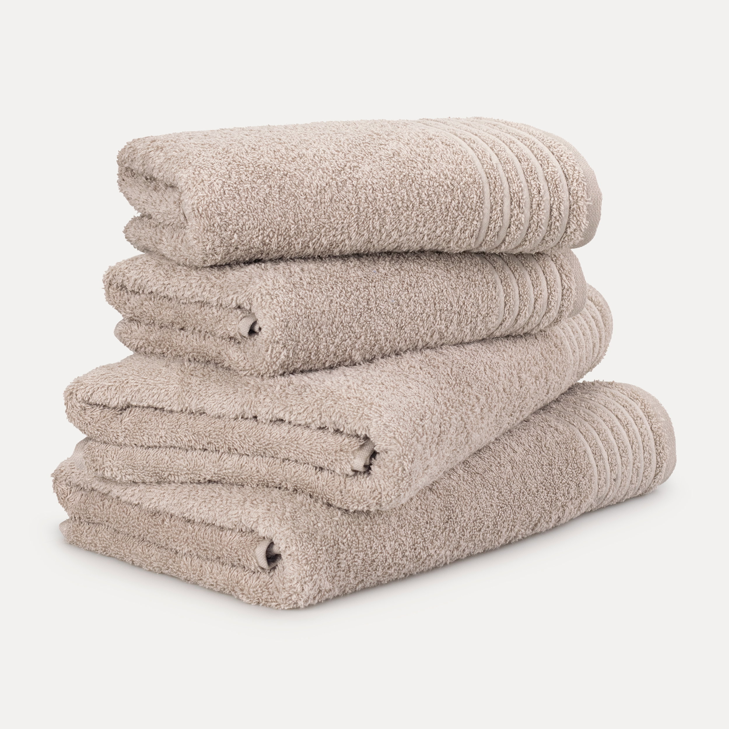 Gestapelte Handtücher — vier beige, flauschig gefaltet mit dekorativen Rippbündchen — als Produktaufnahme auf neutralem, hellem Hintergrund.
